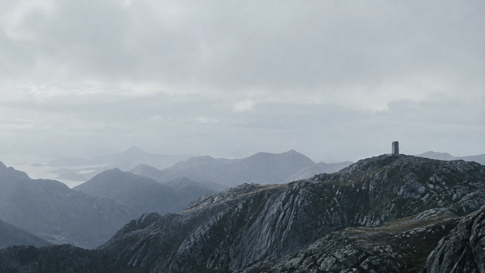 A remote mountain ridge and solitary concrete structure beneath a vast, quiet sky